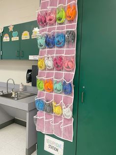 a kitchen with green cabinets and white tile flooring next to a pink towel rack