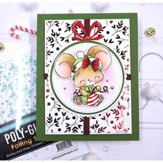 a christmas card with a mouse holding a candy cane in it's hand, on top of a table