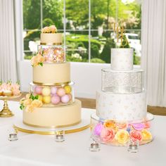 three tiered wedding cake with flowers on the side and other desserts in front