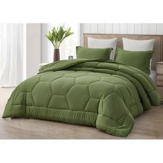 a bed with green comforter and pillows