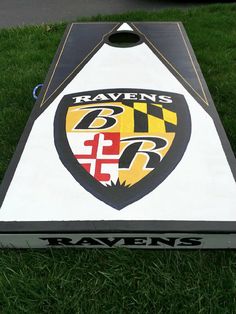 a close up of a cornhole game in the grass with raven's logo on it