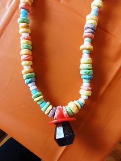 a necklace made out of colorful beads on an orange surface with a black object in the middle