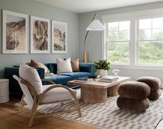 a living room filled with furniture next to two large windows and a rug on top of a hard wood floor