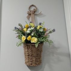 a basket hanging on the wall with flowers in it