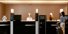 two women are standing at the front desk of a hotel with luggage in hand and one woman is wearing a chef's hat