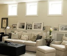 a living room filled with white furniture and pictures on the wall above it's fireplace