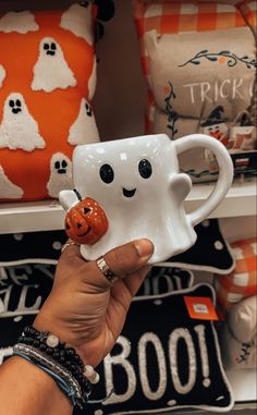 a hand holding a white coffee mug with a smiling face on it's side