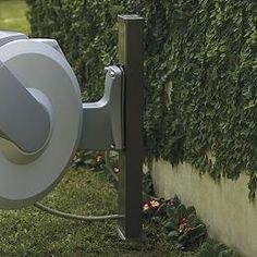 a white toilet sitting on top of a lush green field next to a wall covered in greenery