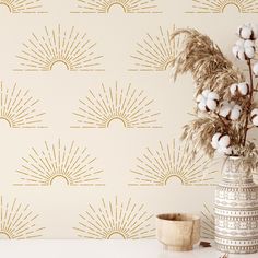 a vase with cotton in it next to a wallpapered background that has sunbursts on it