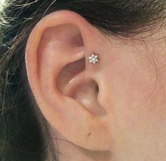 a close up of a person's ear with a small white flower on it