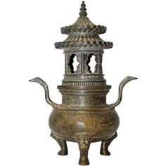 an old metal teapot with two people on it's sides and a bell tower in the middle