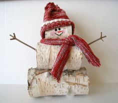 a snowman made out of birch logs wearing a red hat and scarf