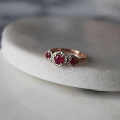 two ruby and diamond rings sitting on top of a white marble slabd countertop