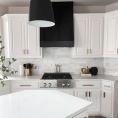 a kitchen with white cabinets and marble counter tops