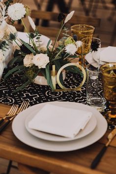 the table is set with white flowers and gold cutlery, along with black napkins