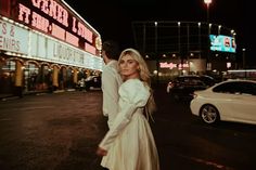 a woman standing next to a man in front of a theater at night with neon lights