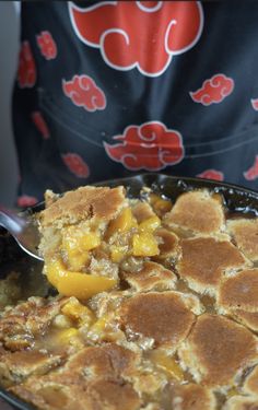 a person holding a spoon in a skillet with some food on top of it