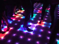 several people are standing on the floor with their feet up and glowing lights all around them