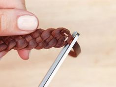 a person holding a pair of scissors in their left hand with a braid on it