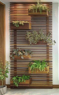 a wall mounted planter filled with lots of plants next to a wooden slatted wall