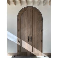 an arched wooden door in a white room