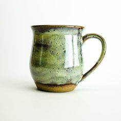 a green and brown cup sitting on top of a white table