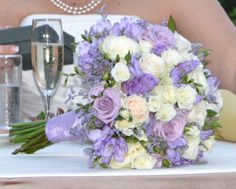 a bridal bouquet sitting on top of a table next to a glass of wine