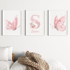 three pink butterfly prints hanging on the wall above a bed with white sheets and pillows