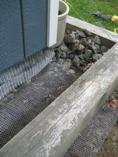 a close up of a metal grate on the side of a building near rocks