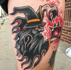 a man's leg with an old school style wizard tattoo on it and a skull in the background