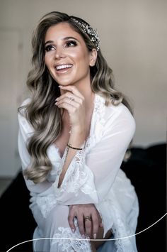 a woman with long hair wearing a tiara and sitting on a couch smiling at the camera