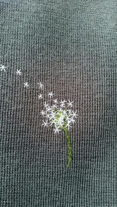 a dandelion with small white flowers in the middle on a gray background,