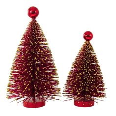 two red and gold christmas trees sitting next to each other on top of a white surface