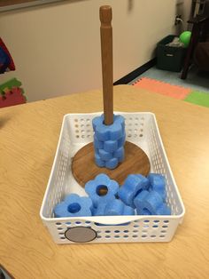 a white basket filled with blue toys on top of a wooden table next to a brown pole