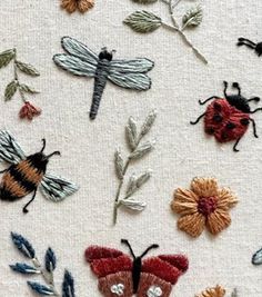 embroidered flowers and bugs on white fabric