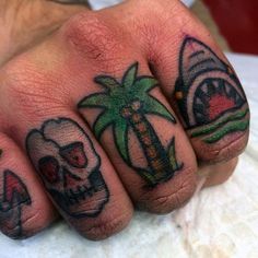 two fingers with tattoos on them, one has a palm tree and the other has a skull