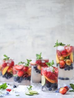 four glasses filled with fruit and ice