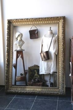 an old fashion shop display with mannequins and hats in a gold frame