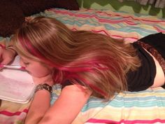 a woman laying on top of a bed with pink hair