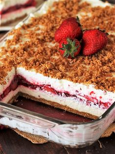 a dessert with strawberries and crumbled toppings in a glass dish on a wooden table