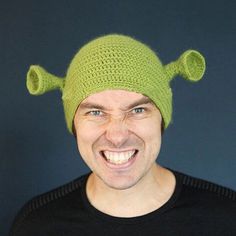 a man wearing a green knitted hat with two horns on it's head