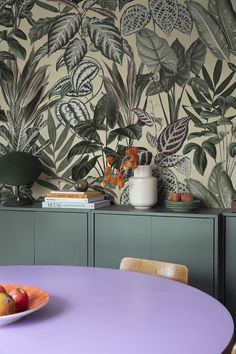 a plate of fruit sits on a table in front of a wallpaper