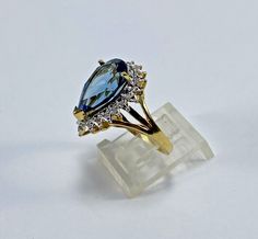 ***😀See Video😀*** 18K Yellow Gold  Blue Topaz and Diamond Ring  Size 7   Very Good Condition with Superficial Wear in the Form of Minor Scratches PEAR SHAPED BLUE TOPAZ Approximate Dimensions: 15.63 x 10.10 x 6.65mm Clarity: slightly included Hue: greenish-blue Tone: medium-light ACCENT DIAMONDS:   Numerous single-cut diamonds weighing approximately 0.10 carat Approximate Overall Color and Clarity: G-H-I-, VS-SI ESTIMATED TOTAL GROSS WEIGHT 7.01 GRAMS ***Buy with Total Confidence*** **For Your Benefit and Protection This Ring Will Be Sent To The GIA for Authentication** If There Are Any Discrepancies in the Above Listing You Will Be Contacted and Advised What's Not to Love About This?  Full 100% Money Back Guarantee Offered Exclusively For the Benefit, Protection and Peace of Mind of Our Pearl Shop, Greenish Blue, See Videos, Halo Diamond Ring, Halo Rings, Buying Jewelry, Blue Tones, Halo Diamond, Blue Topaz