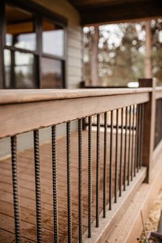 a wooden porch with metal railings next to a house