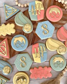 decorated cookies with harry potter symbols on top of a wooden table next to beads and tassels