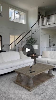 a living room filled with white furniture and a staircase leading up to the second floor