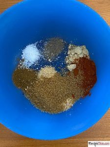 a blue bowl filled with spices on top of a wooden table