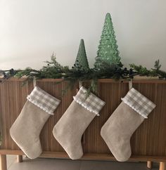 three christmas stockings hanging on a wooden shelf