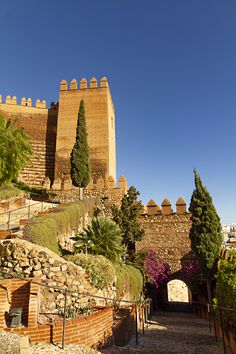 an old brick castle with trees and bushes on the side