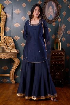 Navy blue short kurta with floral embroidered motifs and gota patti trim on the border. Comes with gharara and organza dupatta.
Component: 3
Pattern: Embroidery
Type Of Work: Thread and Gota Patti
Neckline: Square
Sleeve Type: Three Quarter
Fabric: Cotton Silk and Organza
Color: Blue
Other Details: 
Gharara with gota patti trims on the hems
Side slits with curved hems
Dupatta with gota patti trim on the border
Occasion: Puja - Aza Fashions Blue Sharara With Gota Work In Chinon, Blue Chinon Sharara With Cutdana Detail, Blue Chinon Sharara For Eid, Blue Unstitched Chinon Sharara, Blue Sharara With Traditional Drape In Chinon, Blue Unstitched Sharara In Chinon, Unstitched Blue Chinon Sharara, Blue Chinon Sharara With Traditional Drape, Designer Blue Chinon Sharara